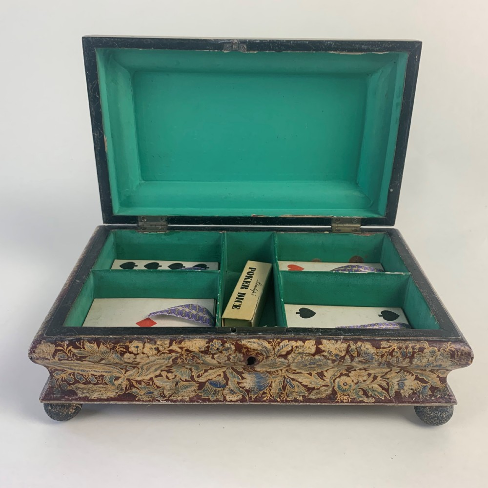 A rectangular early 19th-century Regency wooden games box, hand-painted with intricate botanical patterns in burgundy, gold, and green, featuring a sarcophagus-style lid and small ball feet. View VII