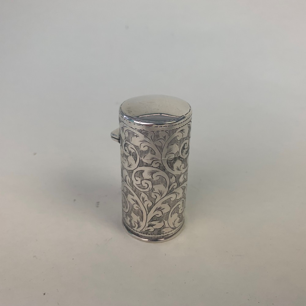 An engraved cylindrical silver scent bottle case with an open hinged lid displaying an internal clear glass bottle with a stopper. View III