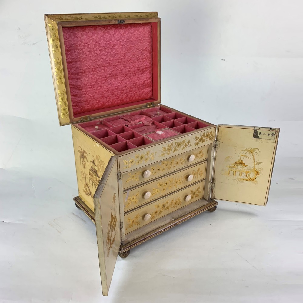 An early nineteenth-century yellow japanned workbox with gilt chinoiserie decoration, a hinged lid revealing red silk compartments, and front doors opening to inner drawers.
