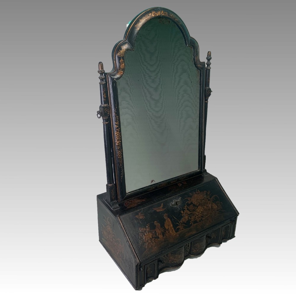A black lacquered toilet mirror featuring an arched frame and gilded Chinoiserie artwork mounted on a miniature slant-front bureau base. View II