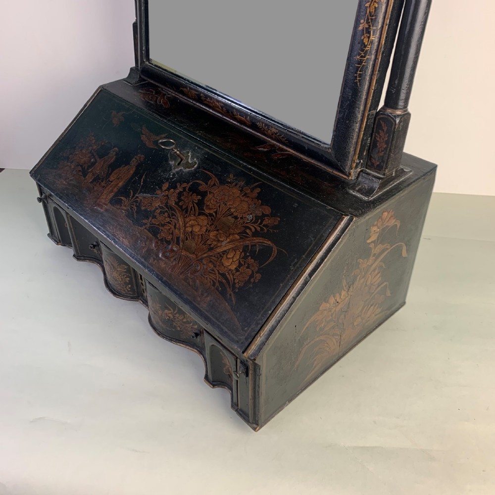 A black lacquered toilet mirror featuring an arched frame and gilded Chinoiserie artwork mounted on a miniature slant-front bureau base. View VI