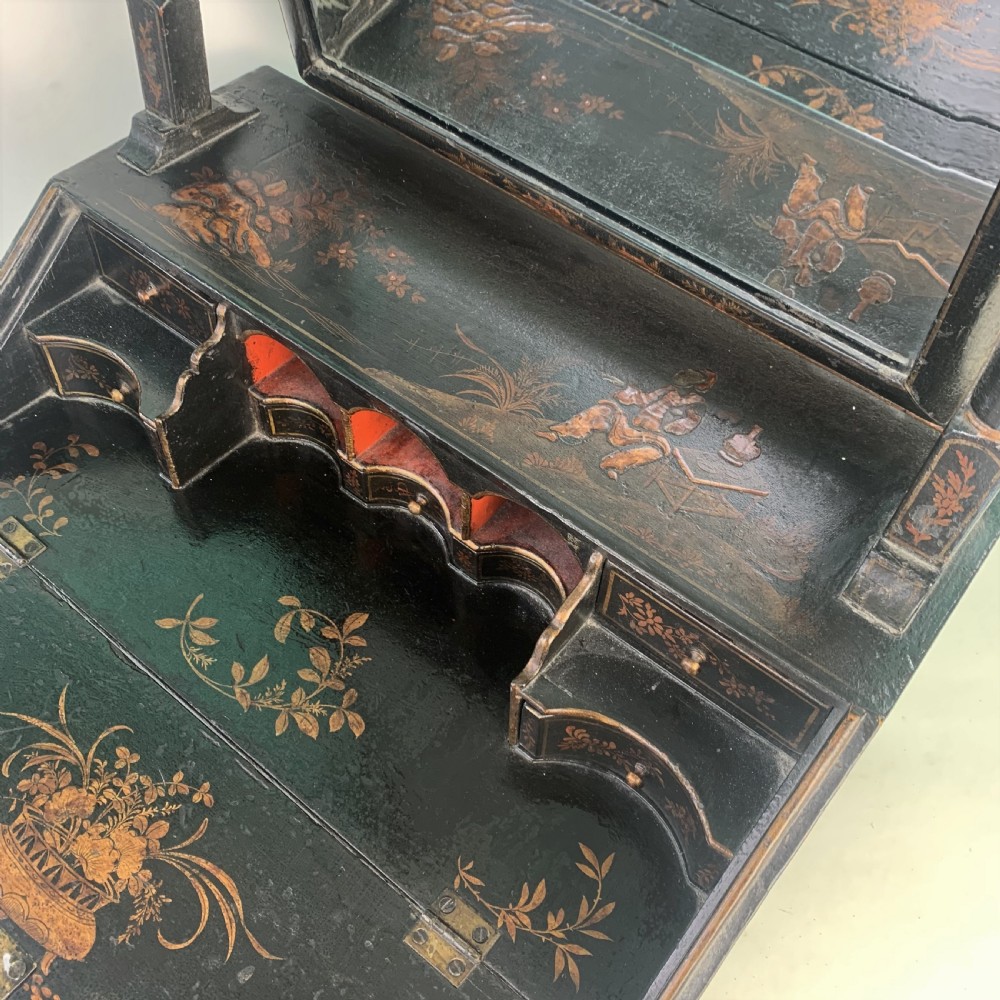 A black lacquered toilet mirror featuring an arched frame and gilded Chinoiserie artwork mounted on a miniature slant-front bureau base. View IX