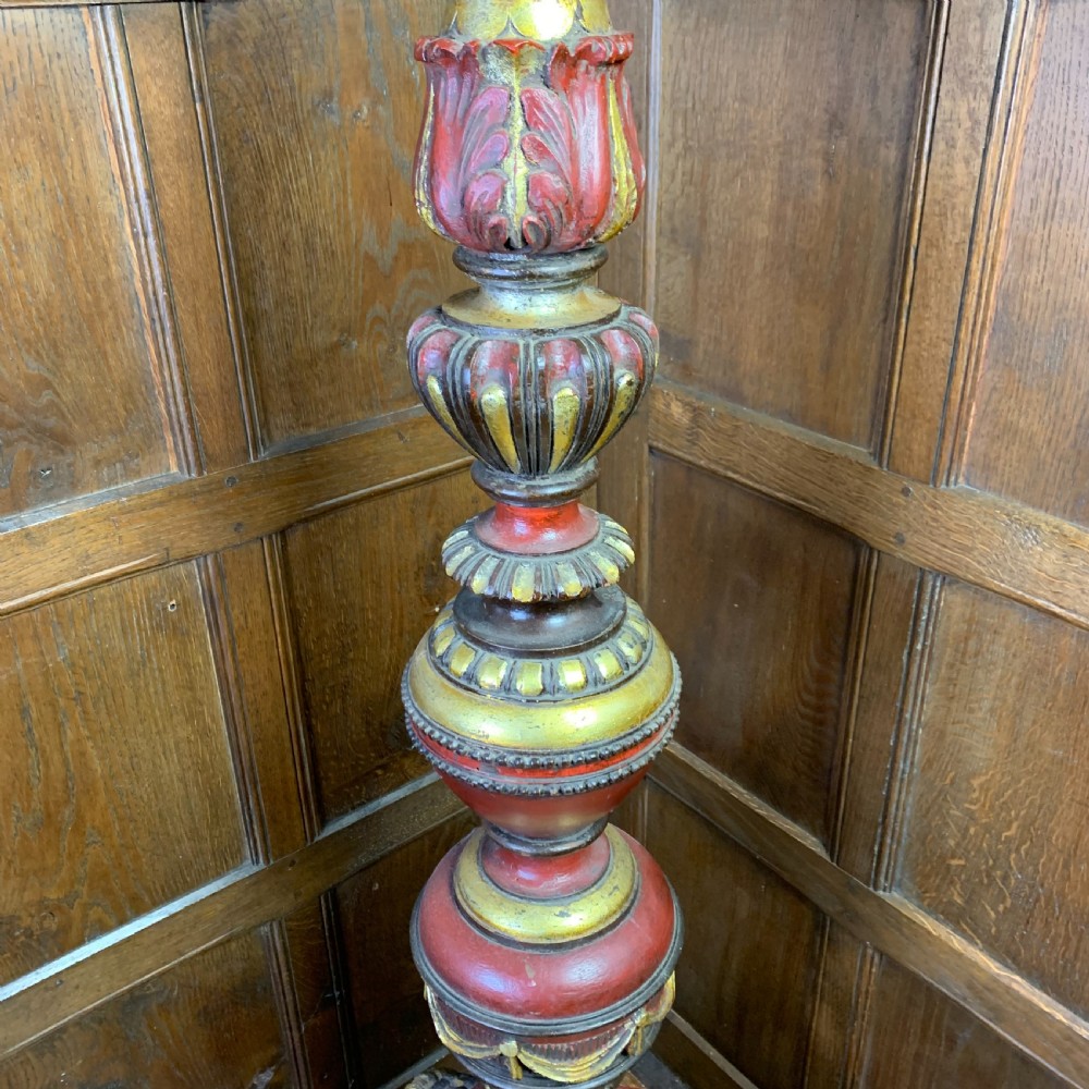 A tall, ornately carved Italian wooden torchiere featuring red and gold polychrome finishes, turned central column sections, and a sculptural scroll base. View III