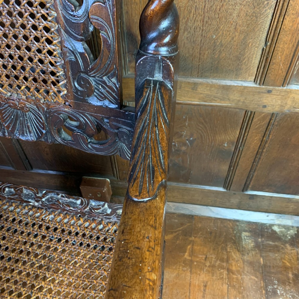 A 17th-century Carolean dark walnut armchair featuring a high backrest with woven cane panels, intricate spiral turned legs, and detailed foliage carving. View IV