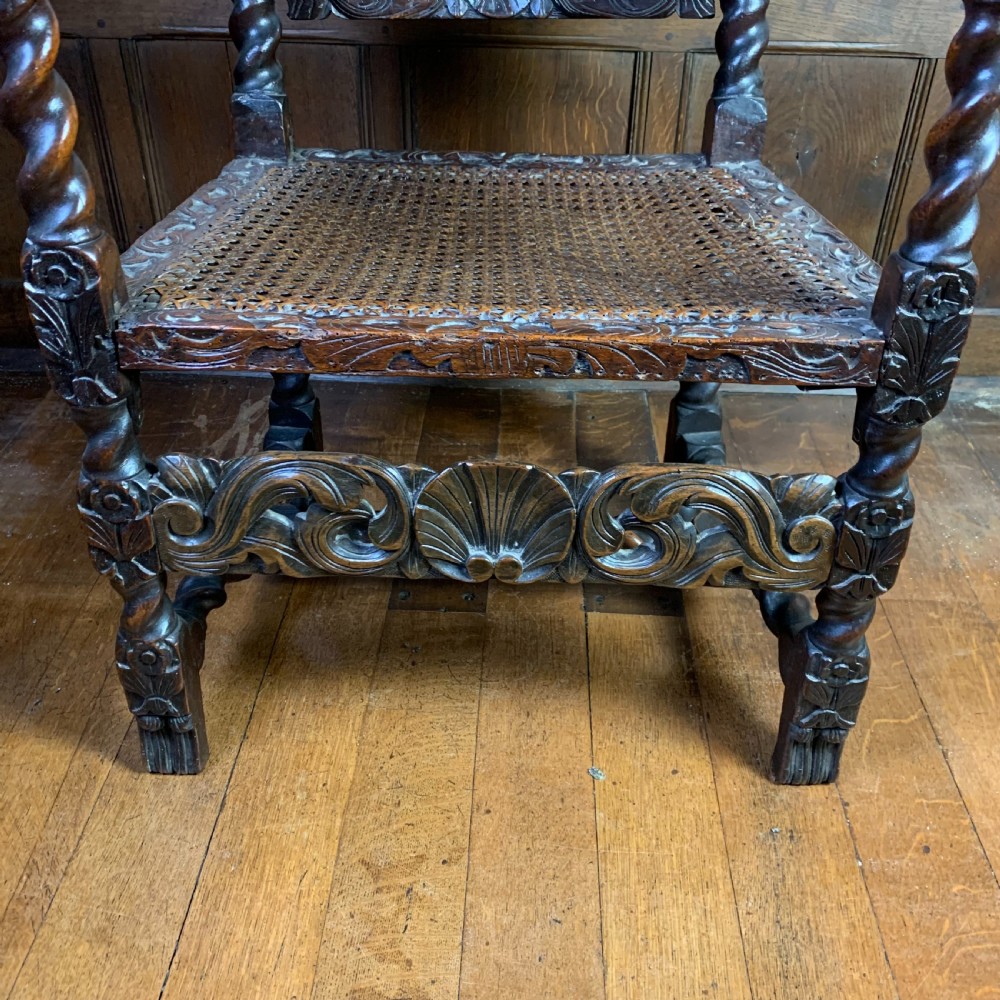 A 17th-century Carolean dark walnut armchair featuring a high backrest with woven cane panels, intricate spiral turned legs, and detailed foliage carving. View VII