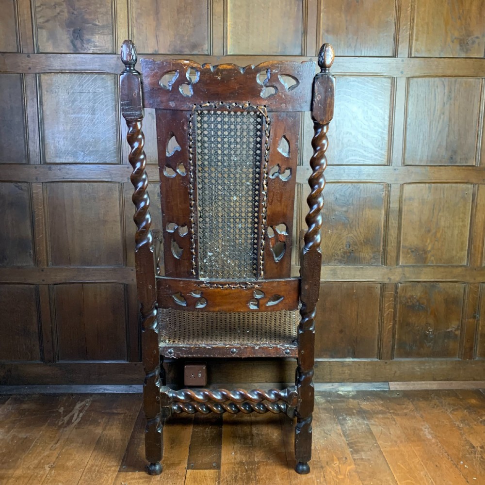 A 17th-century Carolean dark walnut armchair featuring a high backrest with woven cane panels, intricate spiral turned legs, and detailed foliage carving. View VIII