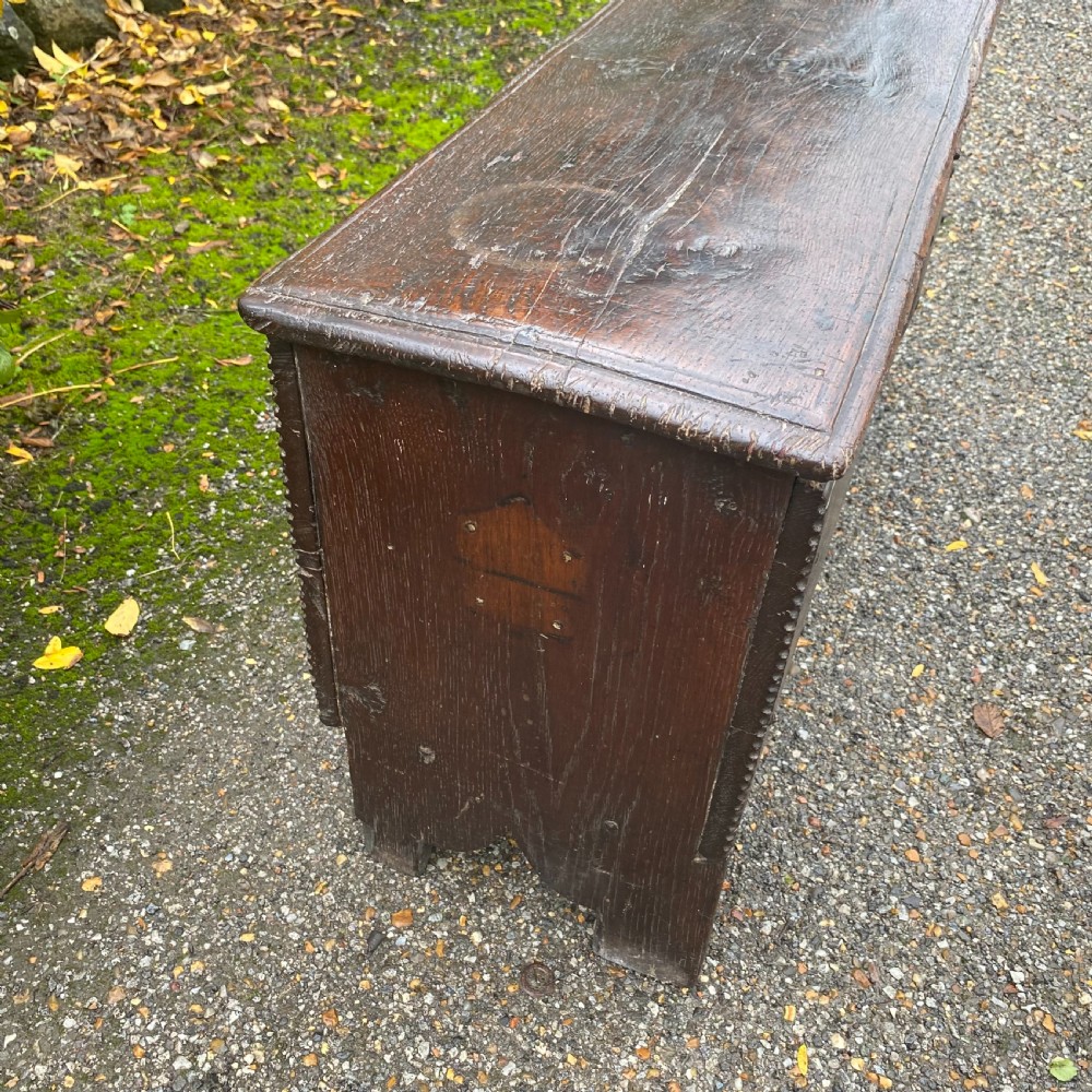 A rectangular dark oak coffer with iron hinges and bracket feet standing outdoors. View VII