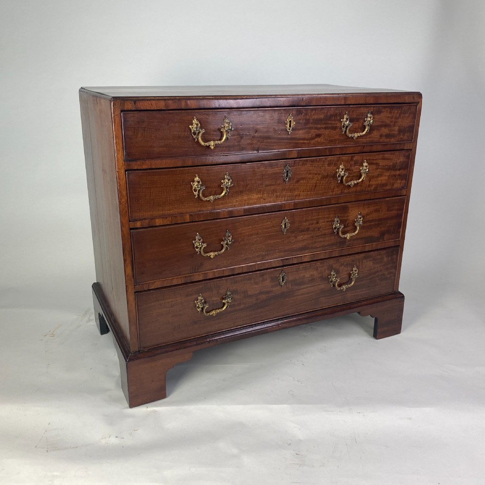 A Georgian Chippendale mahogany chest of drawers featuring four graduated drawers with brass handles, resting on bracket feet. View II