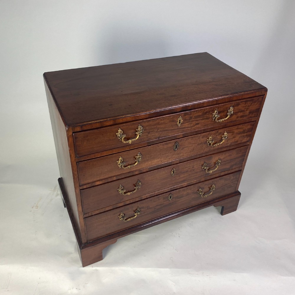 A Georgian Chippendale mahogany chest of drawers featuring four graduated drawers with brass handles, resting on bracket feet. View III