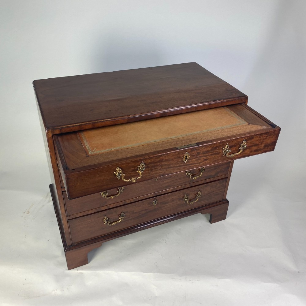 A Georgian Chippendale mahogany chest of drawers featuring four graduated drawers with brass handles, resting on bracket feet. View V