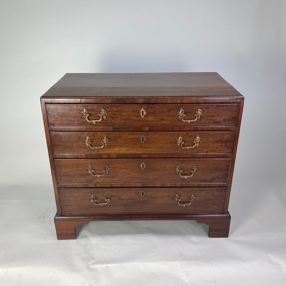 A Georgian Chippendale mahogany chest of drawers featuring four graduated drawers with brass handles, resting on bracket feet. View VIII