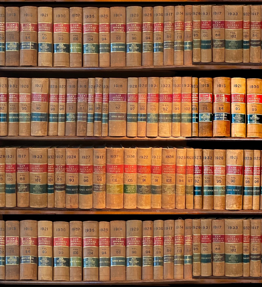 A continuous shelf run of uniform antique leather-bound Law Journal Reports featuring tan calfskin spines, contrasting red and dark labels, and gilt lettering.