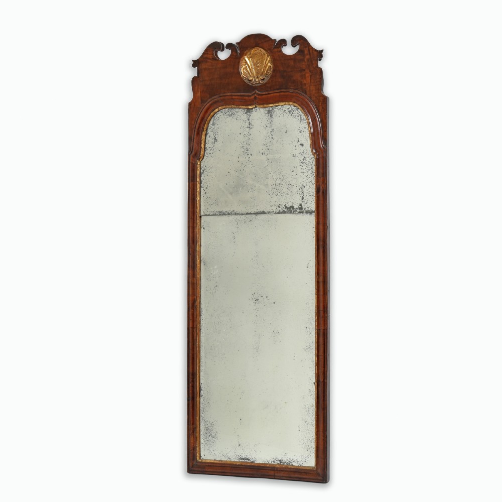 A tall Queen Anne walnut pier mirror featuring an arched frame with a carved gilded shell crest and two-section foxed mirror glass. View IV