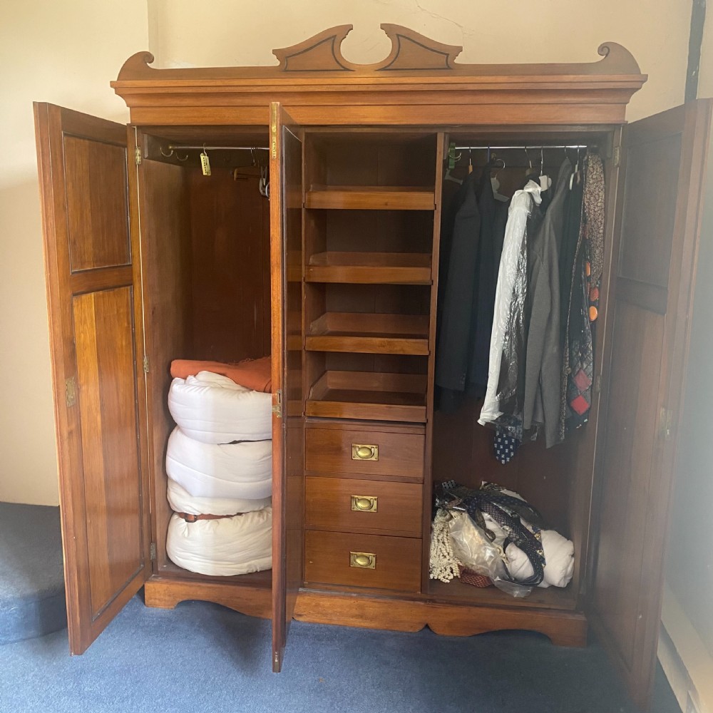 A nineteenth-century Victorian walnut triple wardrobe featuring a central full-length mirrored door flanked by two carved wooden panel doors and topped with a decorative pediment. View VII