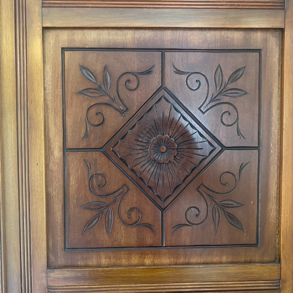 A nineteenth-century Victorian walnut triple wardrobe featuring a central full-length mirrored door flanked by two carved wooden panel doors and topped with a decorative pediment. View IX