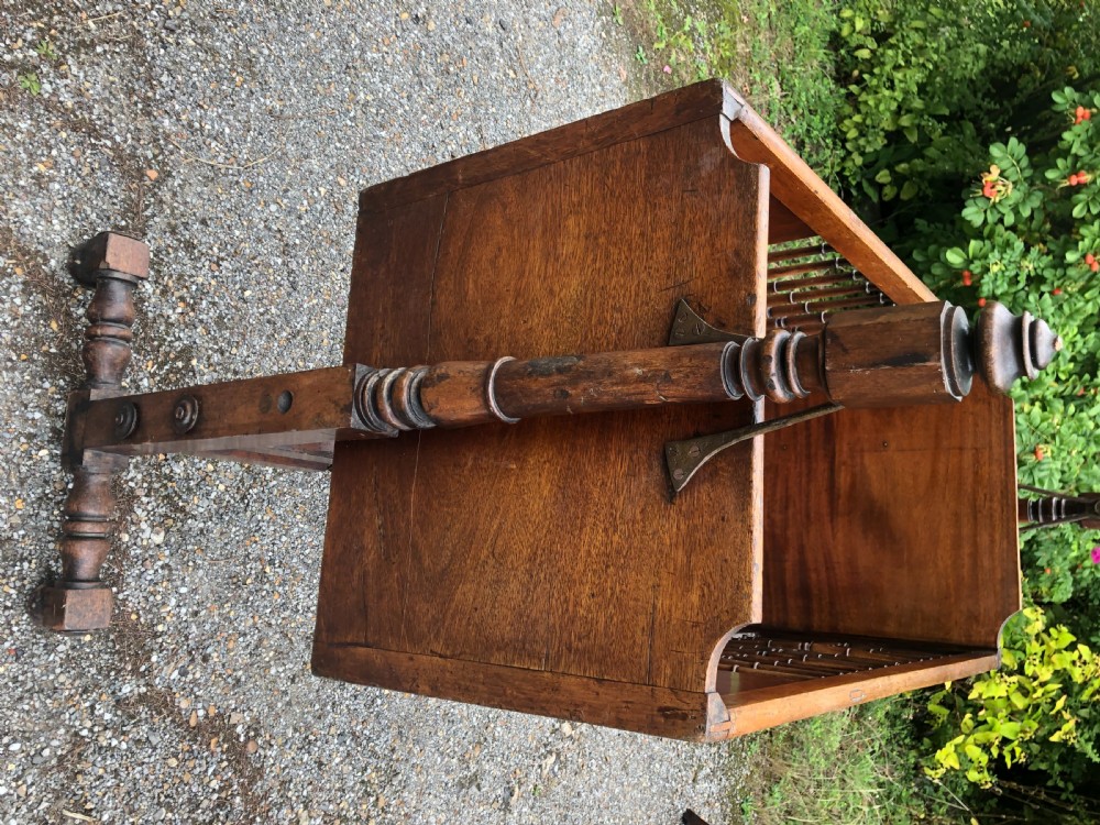 A nineteenth-century wooden rocking cradle featuring turned spindles, solid headboards, and a standing frame with castors. View VII