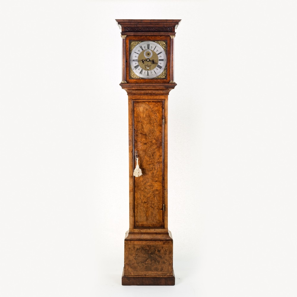 An eighteenth-century burr walnut longcase clock featuring a square brass dial, silvered chapter ring, and moulded pedestal base.