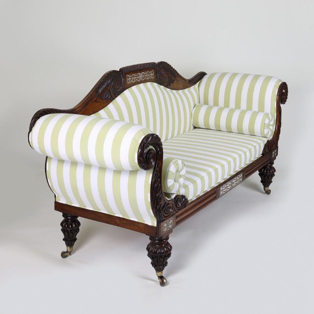 A Regency mahogany scroll end sofa upholstered in green and white striped fabric with matching bolster cushions and turned legs on brass castors. View III