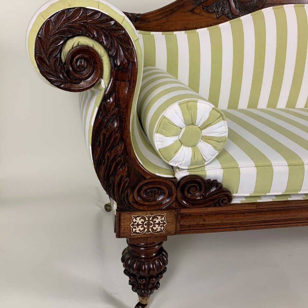 A Regency mahogany scroll end sofa upholstered in green and white striped fabric with matching bolster cushions and turned legs on brass castors. View IV