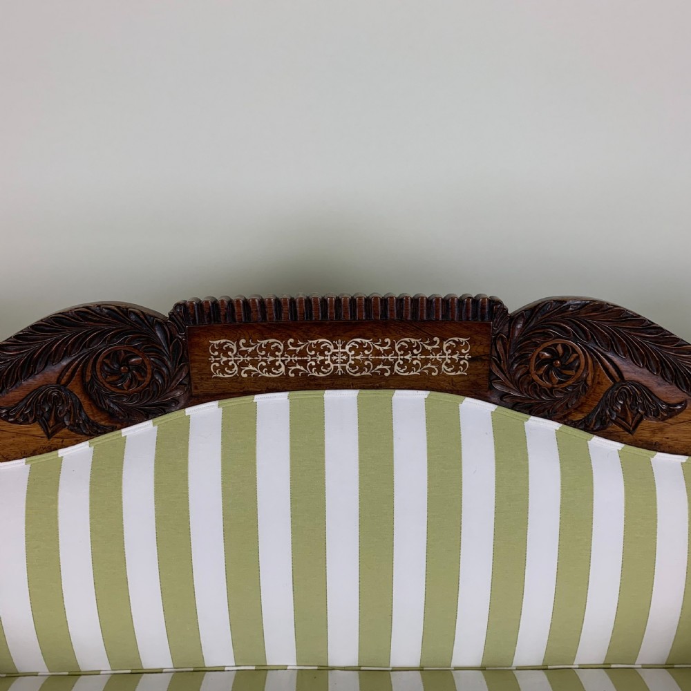 A Regency mahogany scroll end sofa upholstered in green and white striped fabric with matching bolster cushions and turned legs on brass castors. View V