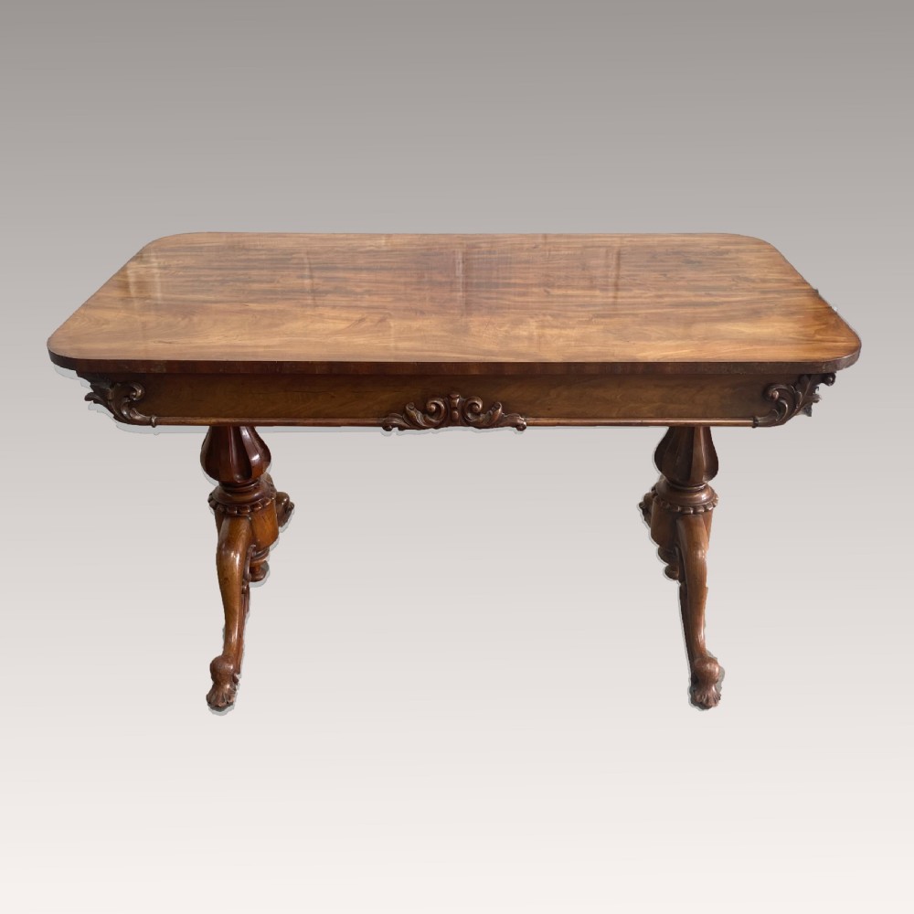 An early 19th-century mahogany library table with a polished rectangular top, carved aprons, and turned pedestal supports resting on scrolled feet. View IV