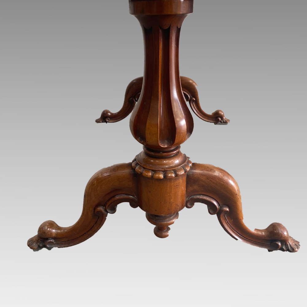 An early 19th-century mahogany library table with a polished rectangular top, carved aprons, and turned pedestal supports resting on scrolled feet. View IX