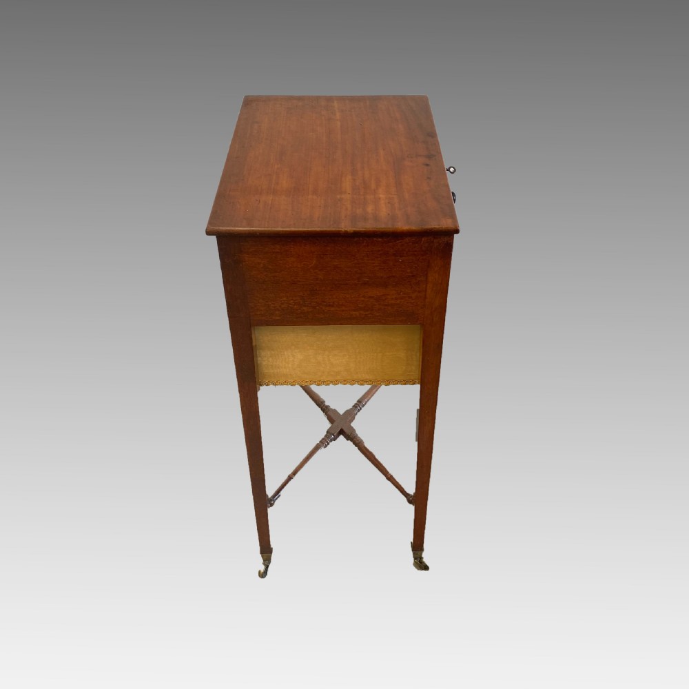 A Georgian mahogany needlework table featuring three drawers, a fabric work pouch, turned X-frame stretcher, and brass castors. View VI