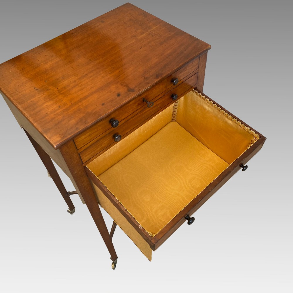 A Georgian mahogany needlework table featuring three drawers, a fabric work pouch, turned X-frame stretcher, and brass castors. View VIII