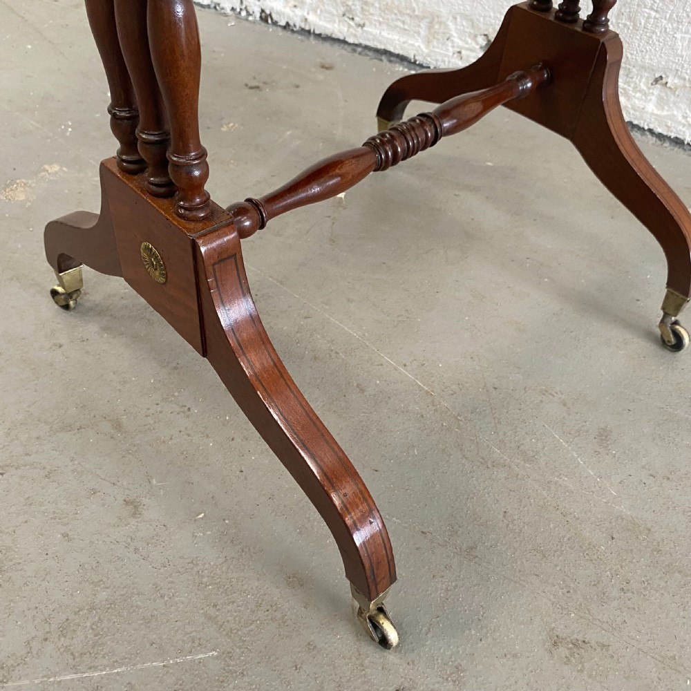 An antique Regency mahogany drop-flap occasional table featuring two drawers with wooden knobs, double turned upright pedestals, and splayed legs on brass castors. View VIII