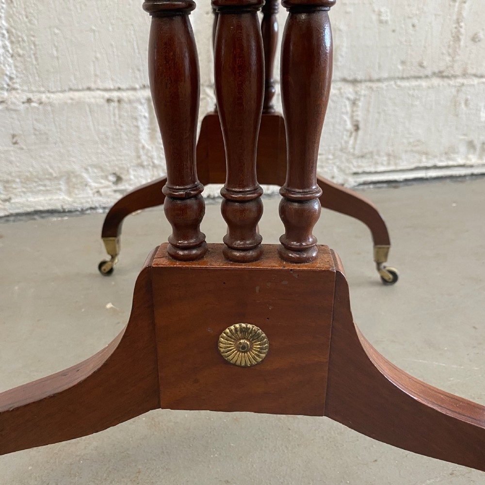 An antique Regency mahogany drop-flap occasional table featuring two drawers with wooden knobs, double turned upright pedestals, and splayed legs on brass castors. View IX