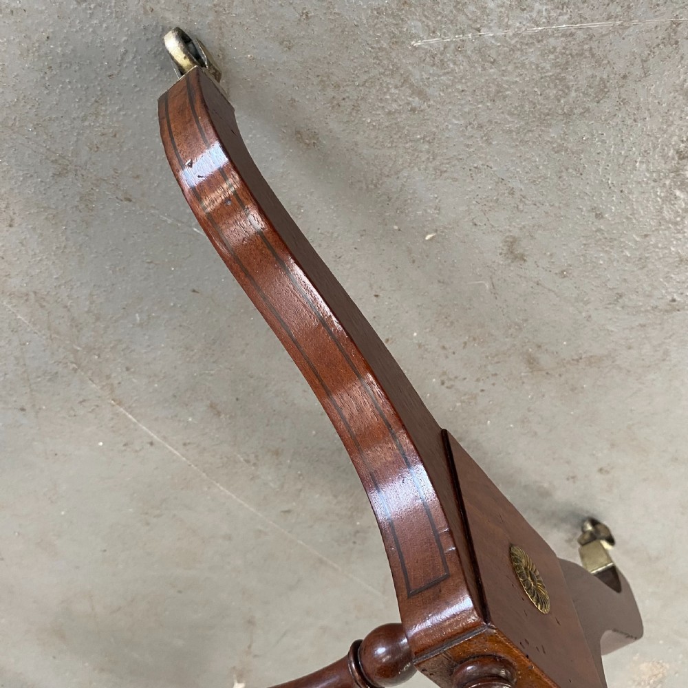 An antique Regency mahogany drop-flap occasional table featuring two drawers with wooden knobs, double turned upright pedestals, and splayed legs on brass castors. View X