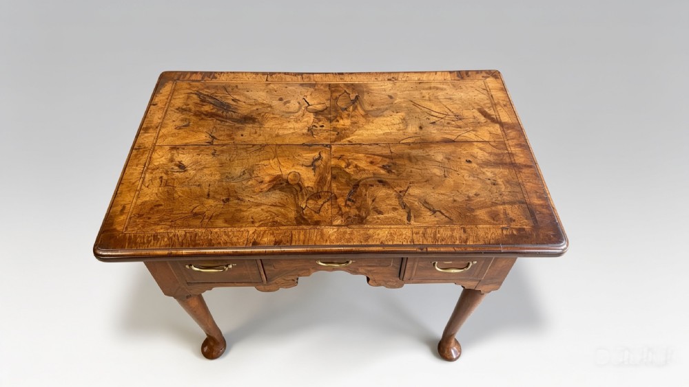 A George II walnut lowboy featuring a veneered top, three brass-handled drawers, a shaped apron, and four cabriole legs terminating in pad feet. View VIII