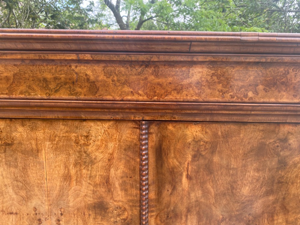 A tall antique burr walnut bonnetiere wardrobe cupboard featuring double panelled doors and a moulded top cornice. View VIII