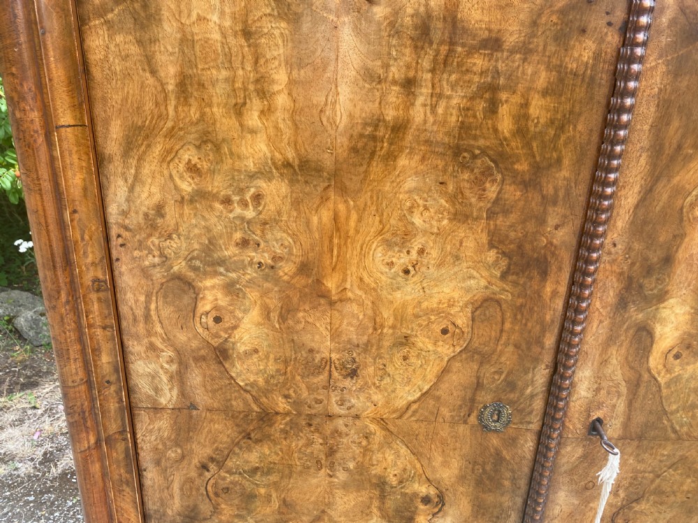 A tall antique burr walnut bonnetiere wardrobe cupboard featuring double panelled doors and a moulded top cornice. View IX