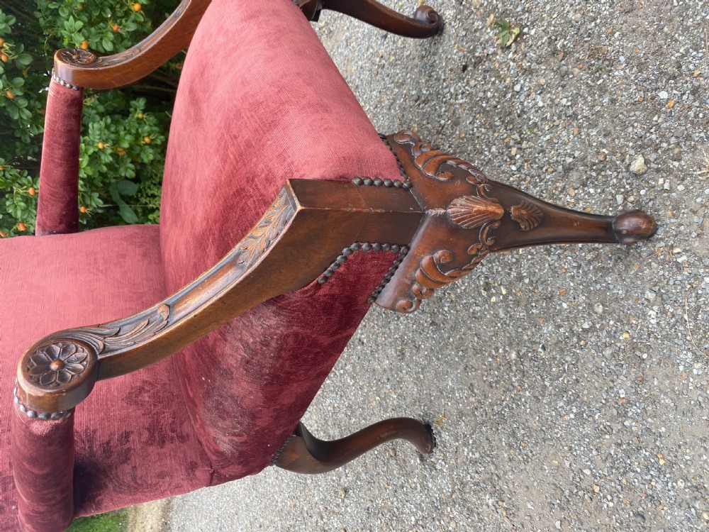 A 19th-century George III style Gainsborough armchair featuring rose pink velvet upholstery, open carved mahogany arms, and carved cabriole legs. View X