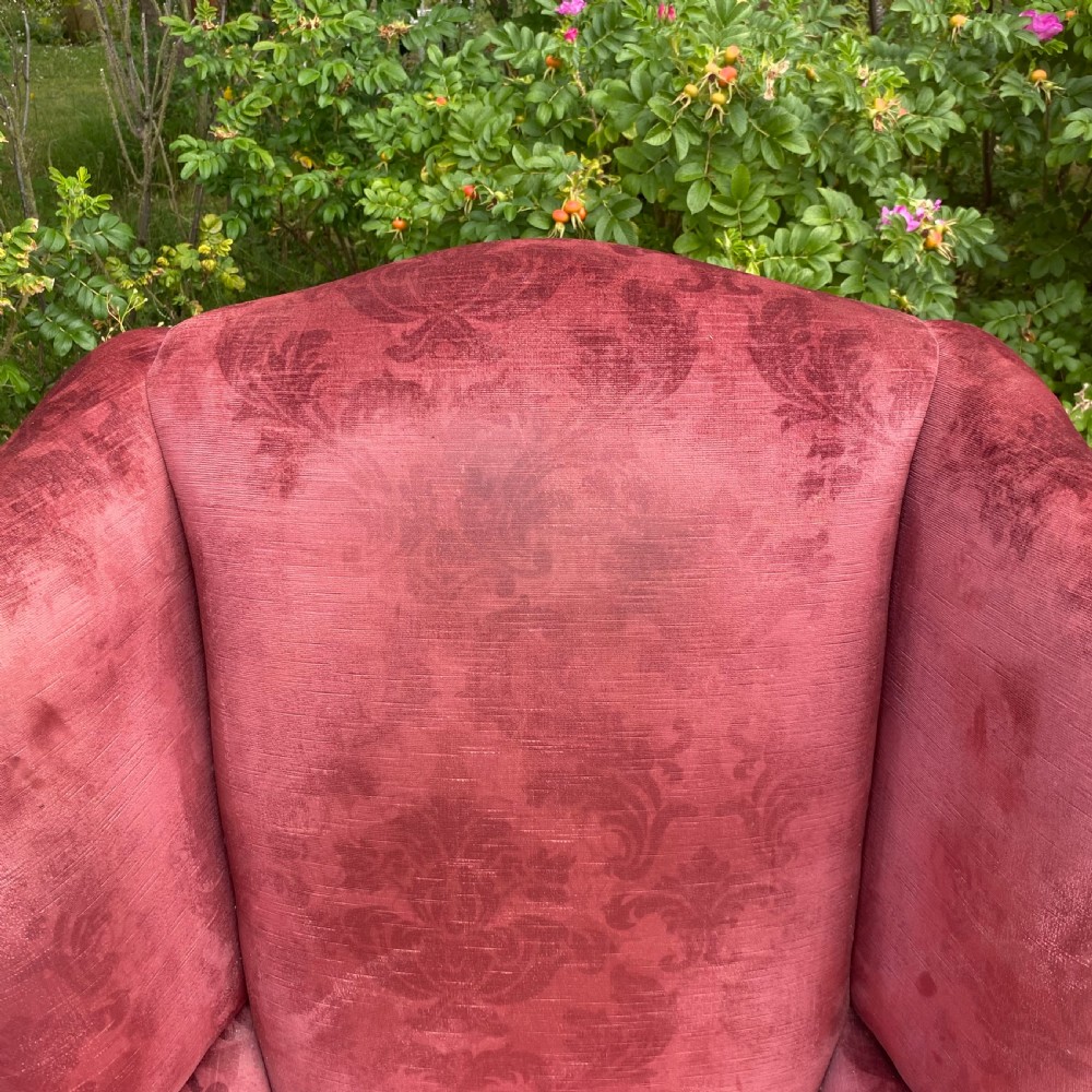 A 19th-century George III style wingback armchair upholstered in rose pink velvet with carved mahogany cabriole front legs and brass stud trimming. View VII