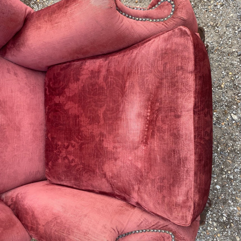 A 19th-century George III style wingback armchair upholstered in rose pink velvet with carved mahogany cabriole front legs and brass stud trimming. View VIII