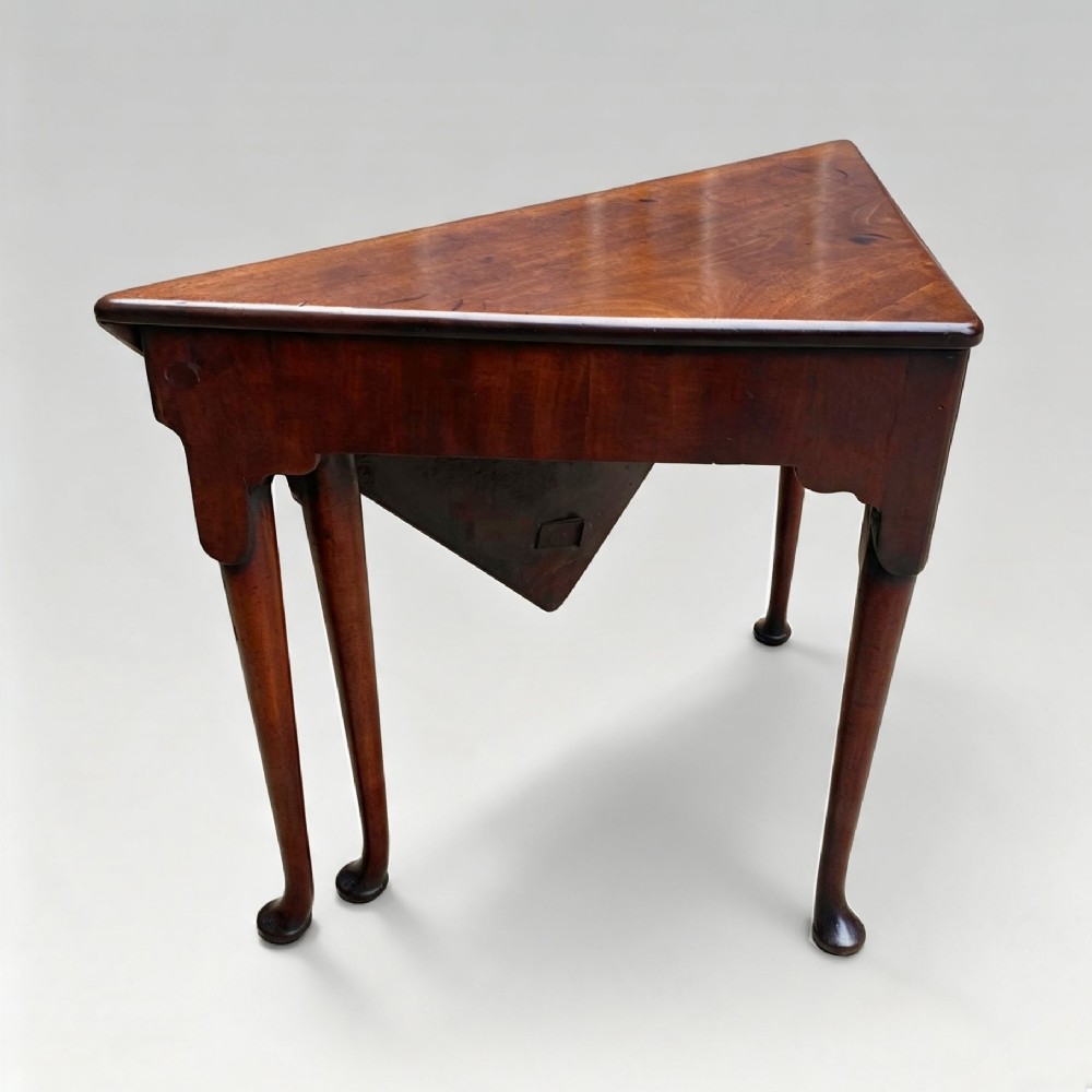 An 18th-century George II triangular mahogany handkerchief table featuring tapered turned legs terminating in pad feet and a keyhole frieze. View II