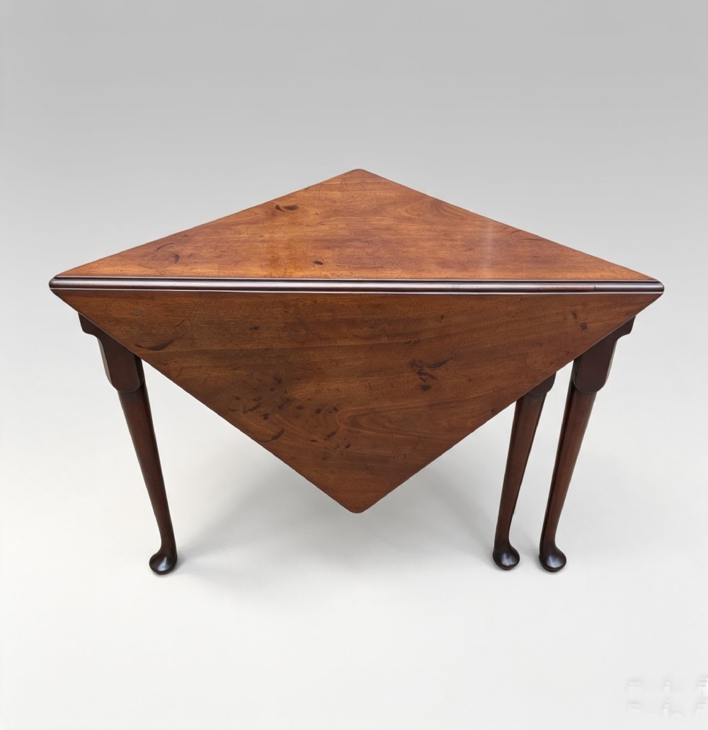 An 18th-century George II triangular mahogany handkerchief table featuring tapered turned legs terminating in pad feet and a keyhole frieze. View V