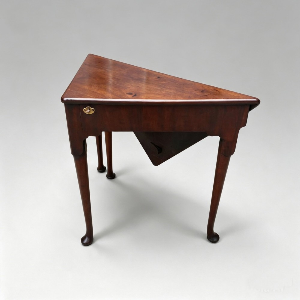 An 18th-century George II triangular mahogany handkerchief table featuring tapered turned legs terminating in pad feet and a keyhole frieze. View VI