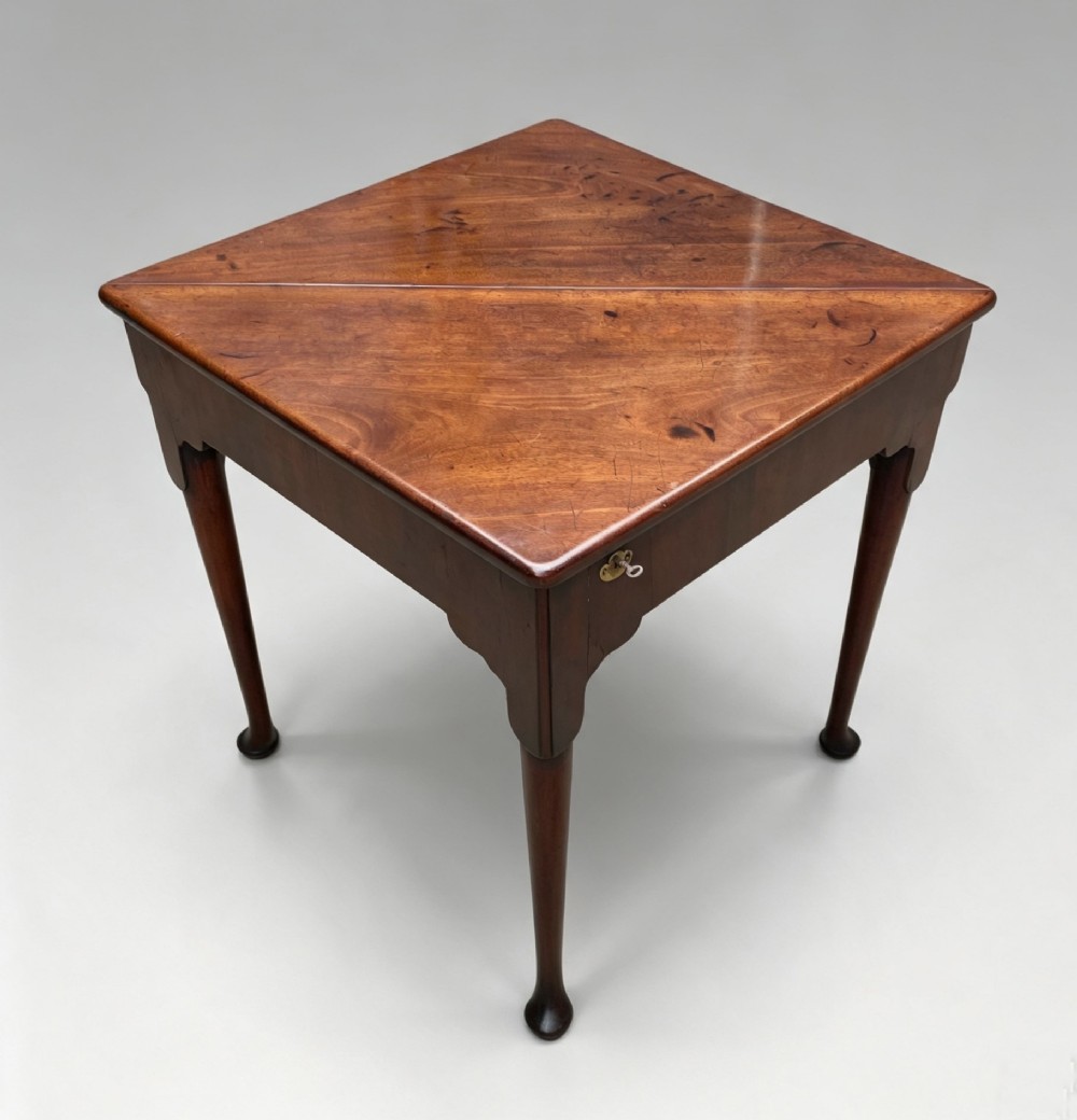 An 18th-century George II triangular mahogany handkerchief table featuring tapered turned legs terminating in pad feet and a keyhole frieze. View VII