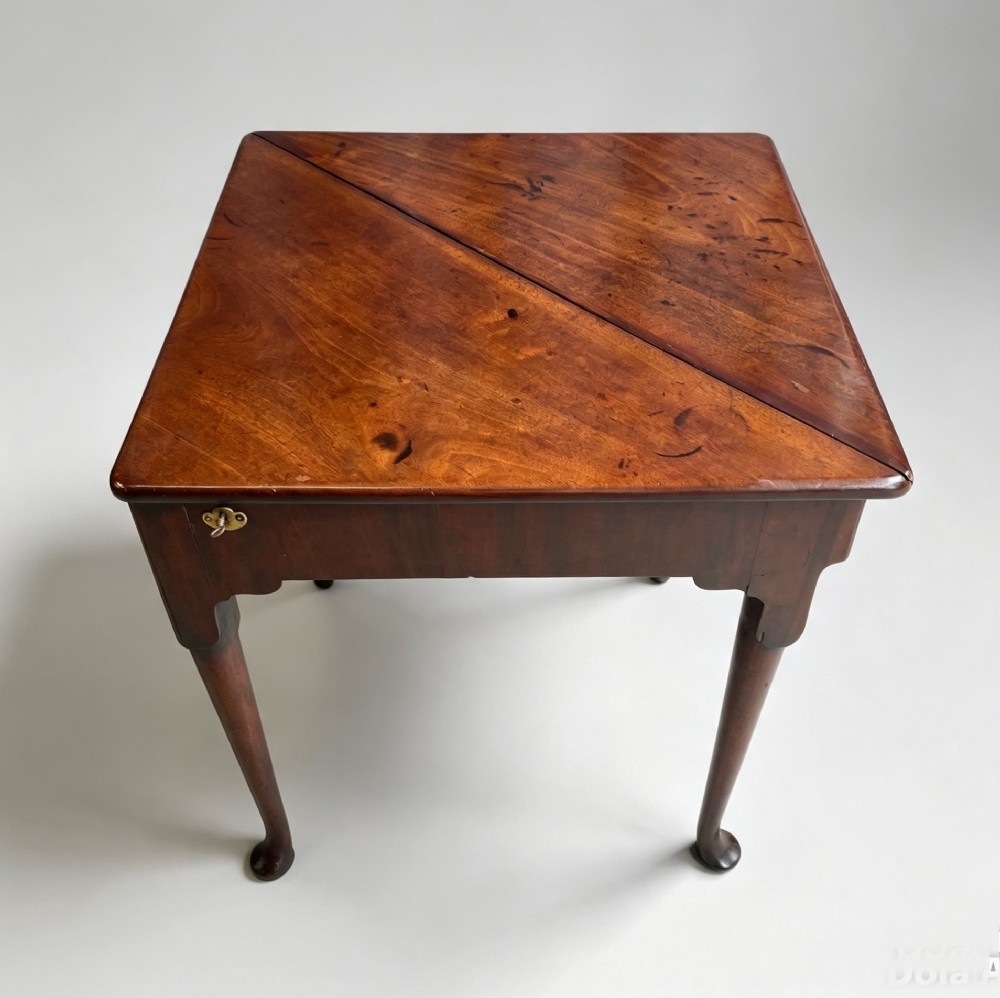 An 18th-century George II triangular mahogany handkerchief table featuring tapered turned legs terminating in pad feet and a keyhole frieze. View IX