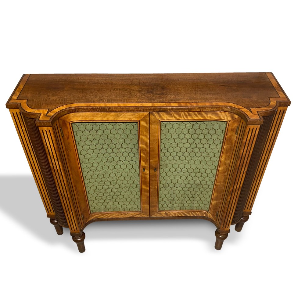 A Georgian satinwood side cabinet featuring two wire-mesh panelled doors lined with green fabric, flanked by fluted pilasters on turned legs. View IV