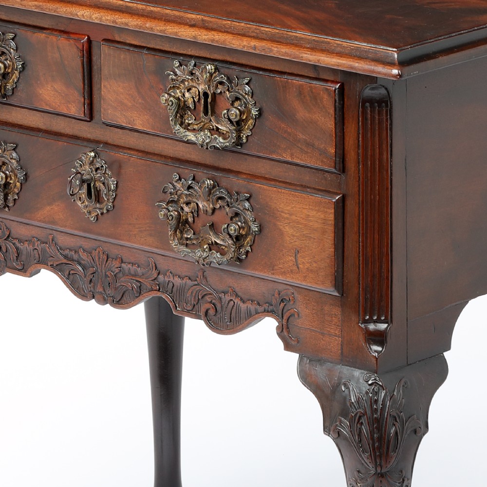 A George II mahogany lowboy side table featuring three drawers, ornate brass backplate handles, carved cabriole legs, and pad feet. View II
