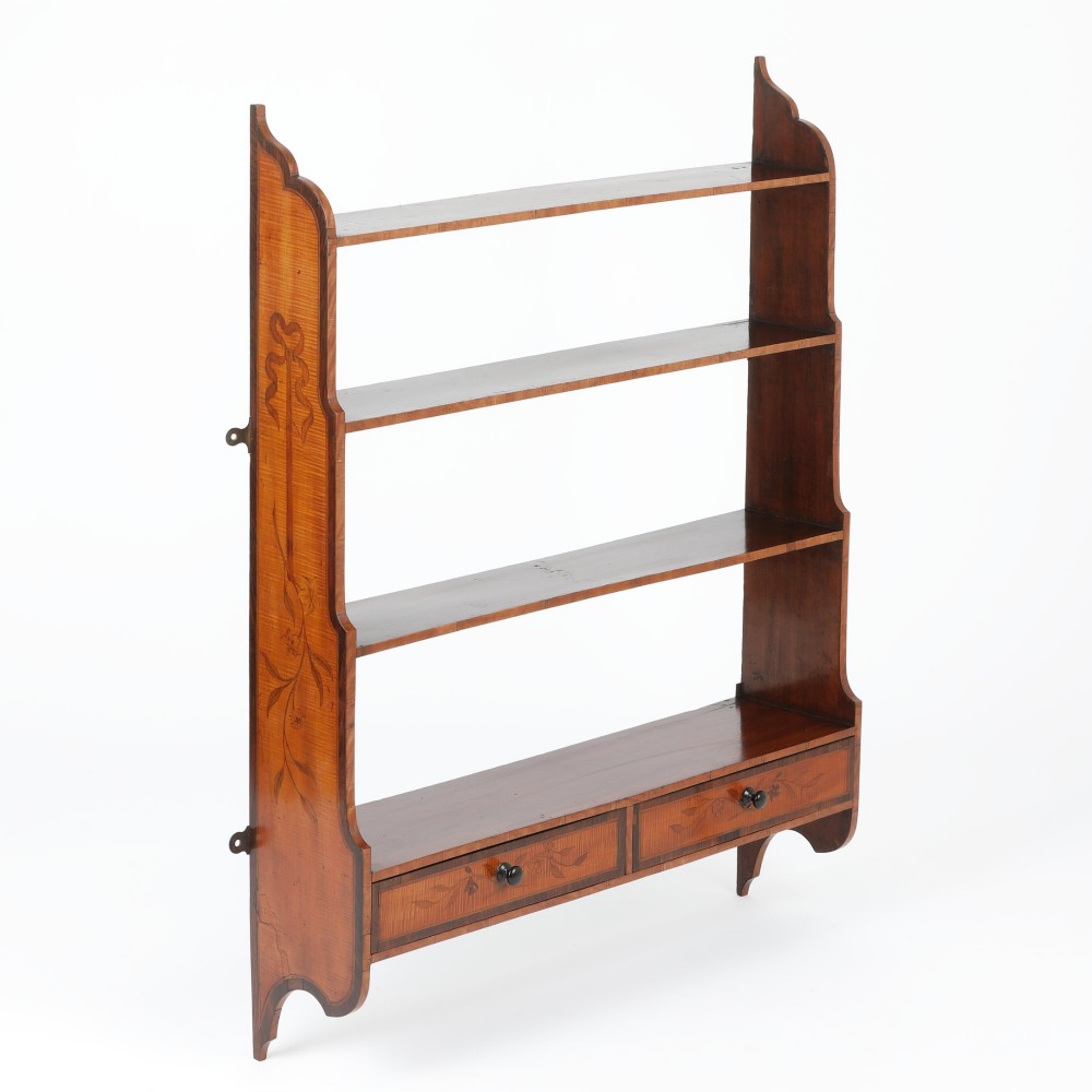 An antique satinwood and mahogany wall-hanging waterfall shelf featuring three open shelves, botanical marquetry inlays, and two small drawers at the base.