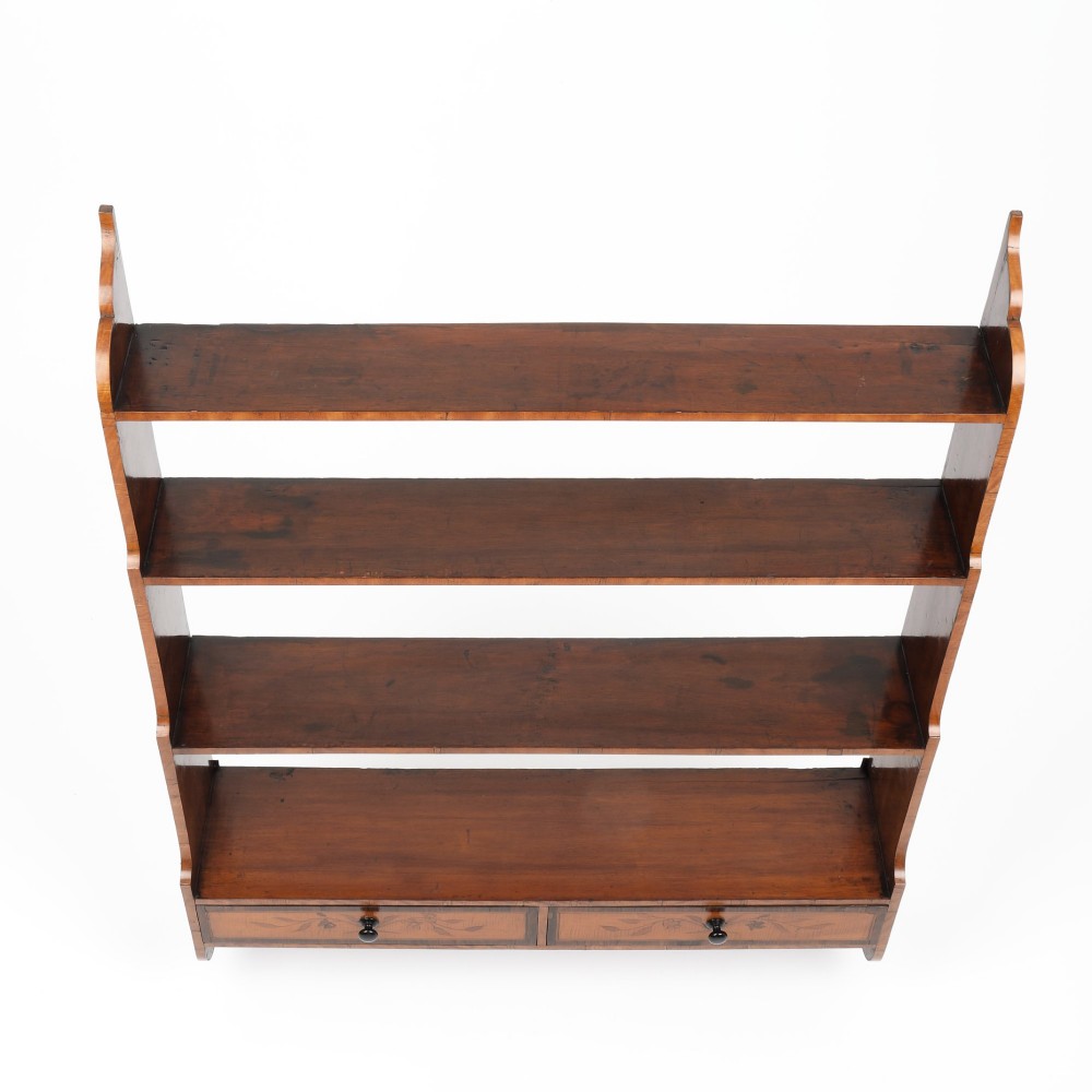 An antique satinwood and mahogany wall-hanging waterfall shelf featuring three open shelves, botanical marquetry inlays, and two small drawers at the base. View V