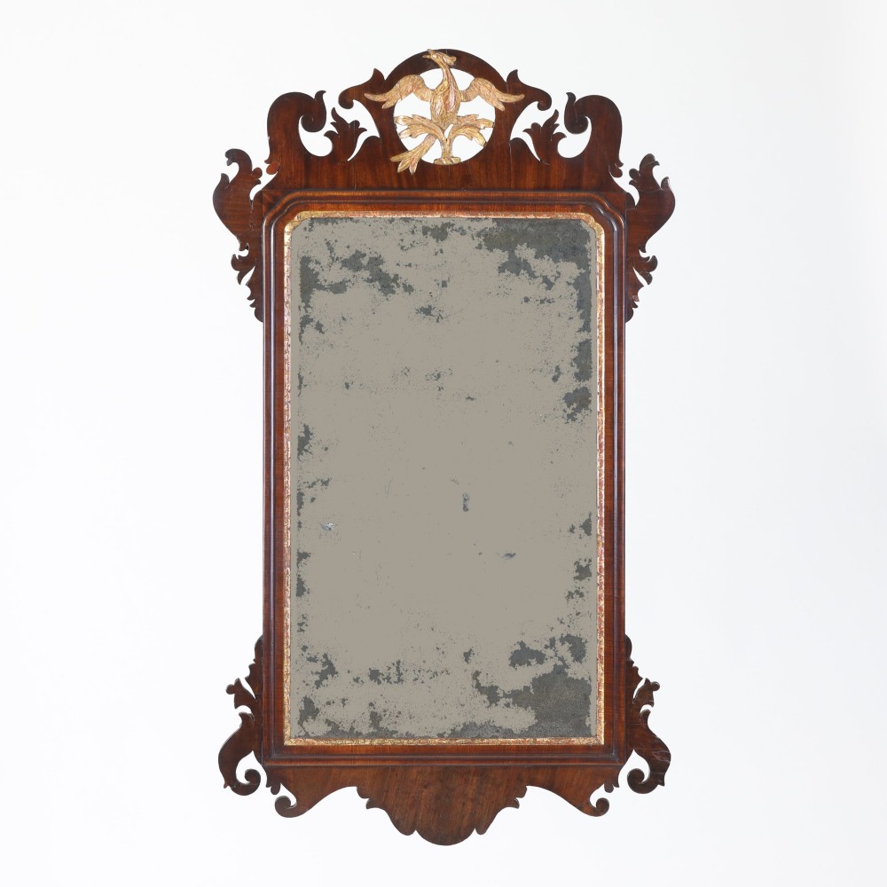 A rectangular Georgian mahogany wall mirror featuring a scroll-cut fretwork frame topped with a gilded ho-ho bird cresting.