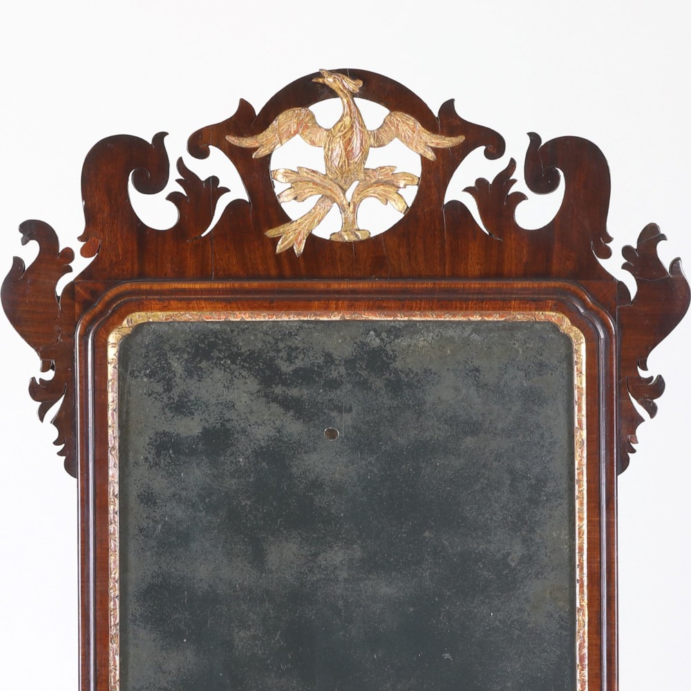 A rectangular Georgian mahogany wall mirror featuring a scroll-cut fretwork frame topped with a gilded ho-ho bird cresting. View II