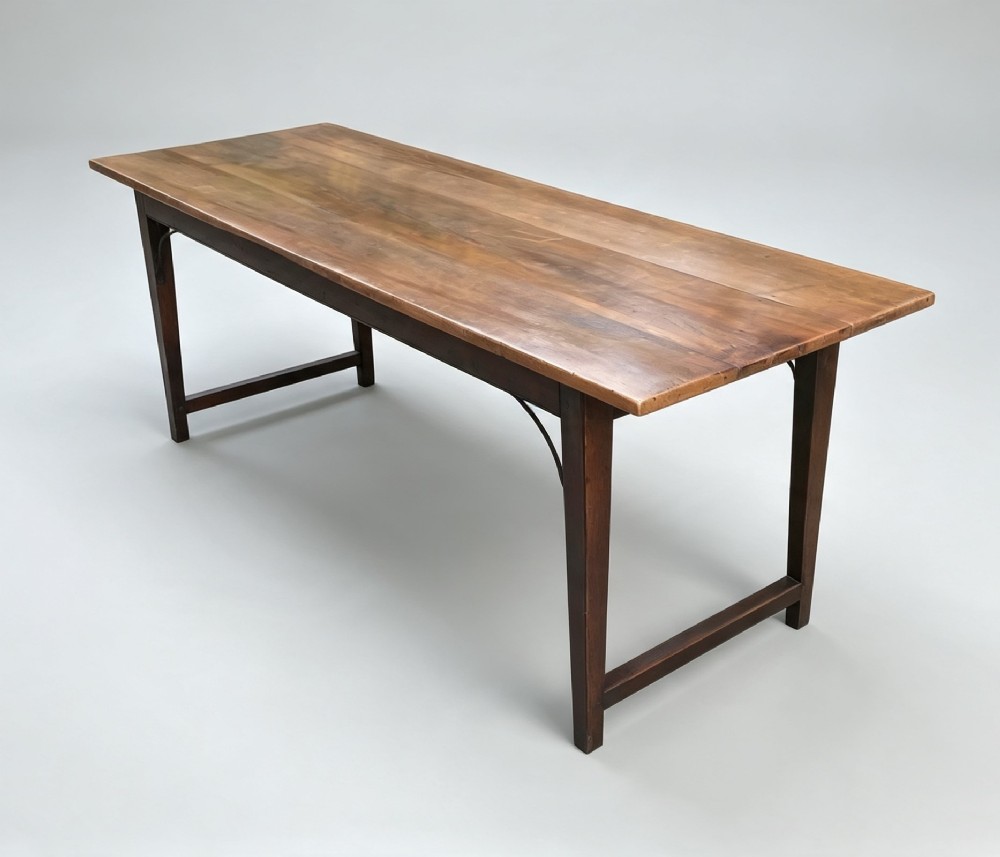 An antique rectangular refectory table made of warm fruitwood timber featuring a multi-plank top, dark legs, and metal corner support braces. View III