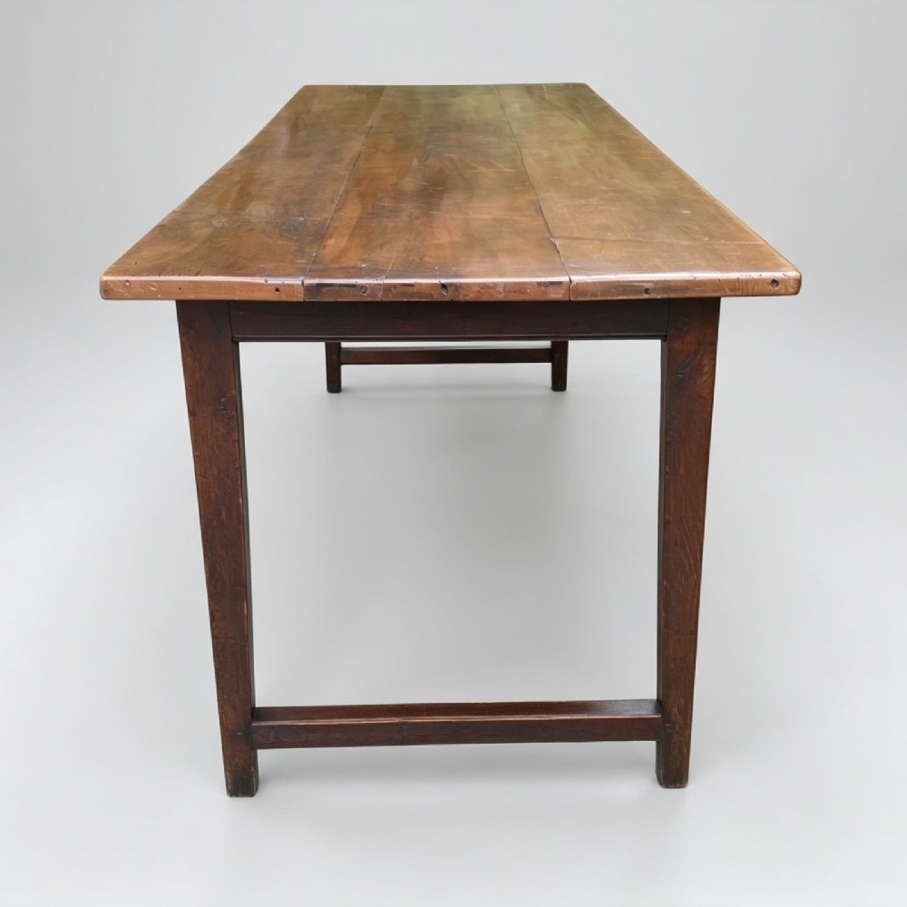An antique rectangular refectory table made of warm fruitwood timber featuring a multi-plank top, dark legs, and metal corner support braces. View V